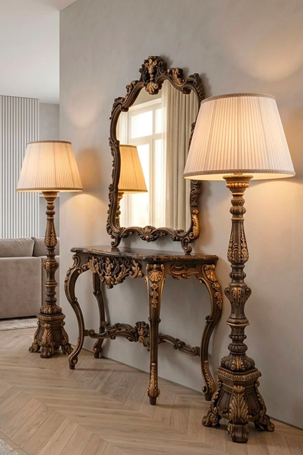Una consolle in stile barocco realizzata in legno intagliato a mano con piano in marmo. Sopra di essa &egrave; collocato uno specchio in stile barocco con cornice in legno intarsiato. Ai lati si trovano lampade da terra barocche, anch'esse realizzate in legno intagliato.